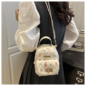 Detail of white mini backpack featuring pink bear and rabbit prints with gold metal chain