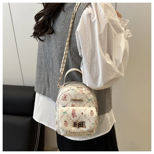 Detail of a mini cream backpack with pink bunny prints and a golden metal clasp closure