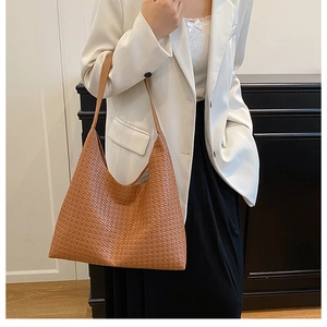 Detailed texture of caramel brown hand-woven leather tote bag on model shoulder