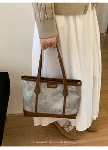 Detail of gray marble textured tote bag with dark brown leather handles and brand tag