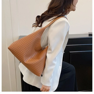 Detailed texture of brown woven hobo shoulder bag styled with a white blazer
