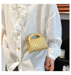 Close-up of golden quilted mini crossbody bag with metal chain strap and fixed handle