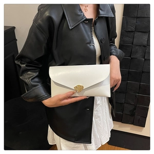 Détail d'une pochette enveloppe blanche élégante avec une boucle en métal doré irrégulière