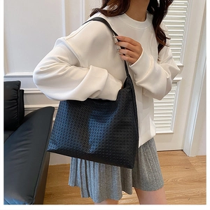 Detailed view of black woven texture and leather strap on a large tote shoulder bag