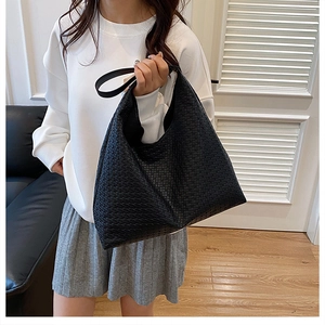 Detail of a large black woven leather tote bag with braided texture for daily commute