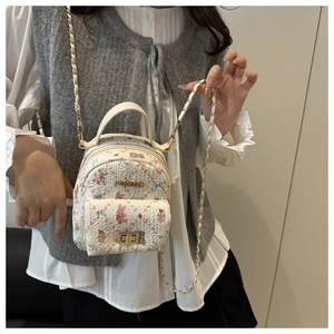 Detail of white mini backpack featuring cute floral prints and gold metal twist lock