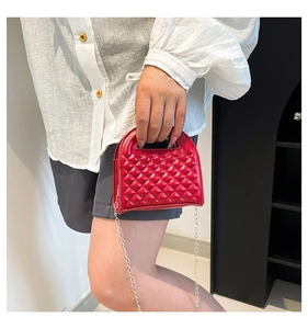 Detailed view of red quilted mini bag with silver chain strap and top handle