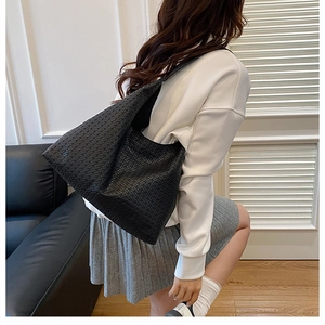 Detailed view of black woven texture on a soft tote bag worn by a model in a room