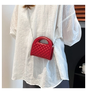 Close-up of red quilted mini crossbody bag with silver chain strap and top handle