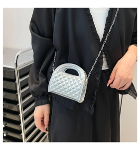 Detail of silver quilted mini crossbody bag with metal handle and chain strap on model