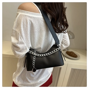 Chic black PU leather baguette bag with thick silver chain worn by a model in lifestyle set