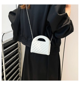 Rear view of a white quilted mini bag with chain strap styled on black outfit