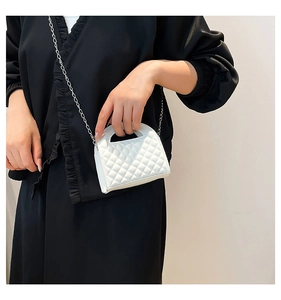 Close-up of white quilted mini bag with silver chain strap shown on a model