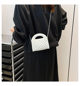 Detailed back view of a white quilted crossbody bag with metal chain strap on model