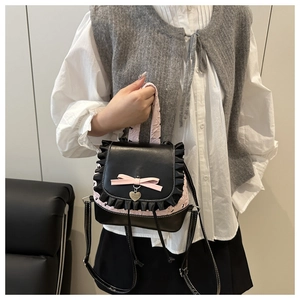 Detail of sweet pink lace trim and heart pendant on a black leather mini backpack