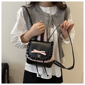 Detail of mini backpack with lace trim, pink silk bow and heart-shaped gold pendant