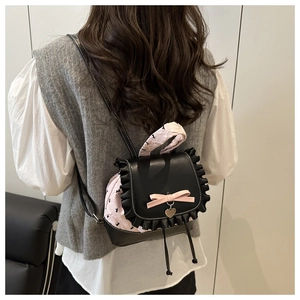 Detail of a mini backpack featuring black lace trim, pink jacquard, and a bow charm