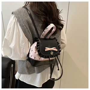 Detail showing pink lace backpack with black ruffle trim and silk bow decoration