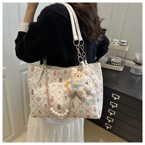 Gros plan d'un sac cabas blanc imprimé avec motifs de dessins animés et chaîne perlée