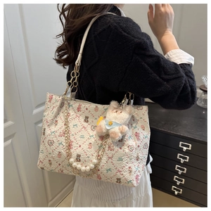 Détail du sac cabas crème avec motifs de dessins animés et accessoire de chaîne en perles