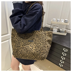 Macro detail of leopard print canvas tote bag featuring an outer pocket with brand patch