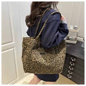 Shoulder view of a large leopard print canvas tote bag showing size and styling on model
