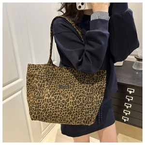 Detailed view of the leopard print canvas tote bag with a black logo patch and shoulder strap