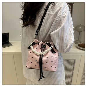 Detail of pink polka dot bucket bag featuring pearl handle and black ribbon bow detail