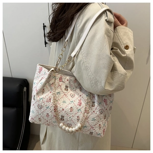 Detailed view of floral tote bag featuring a pearl pendant and golden metal chain strap