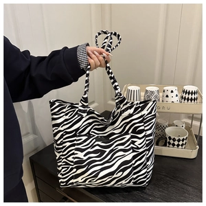 Detailed close-up of a zebra pattern canvas tote bag with a front pocket and logo patch