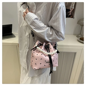 Detail of pink leather bucket bag with pearl handle and bow patterns on model
