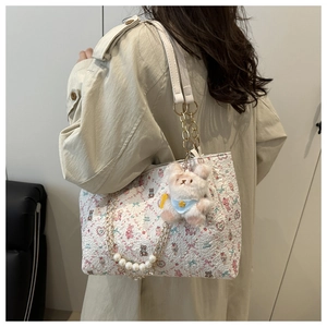 Détail du sac cabas crème avec motifs de dessins animés, chaîne de perles et breloque lapin