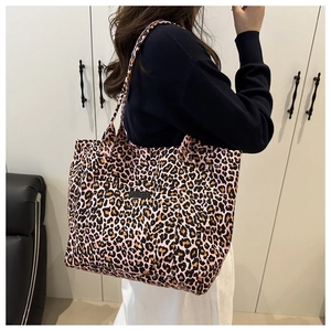 Detail of large capacity tote bag featuring pink leopard print and brand label on shoulder