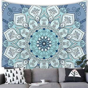 Blue and white mandala tapestry hanging on a white wall above a modern grey sofa