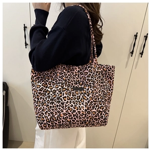 Detail of pink leopard print tote bag with black logo tag and canvas shoulder straps