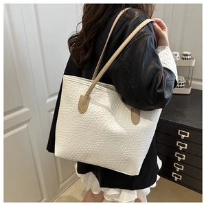 Detail of white woven texture tote bag with khaki straps on shoulder in home setting