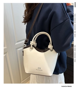Detail shot of bicolor bucket bag showing knotted handle and adjustable shoulder strap
