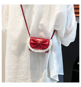 Close-up of red patent leather purse featuring a bow and white lace trim detail