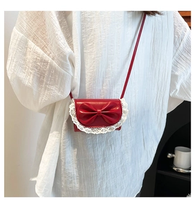 Detailed close-up of a red mini crossbody bag with lace edges and a bow decoration