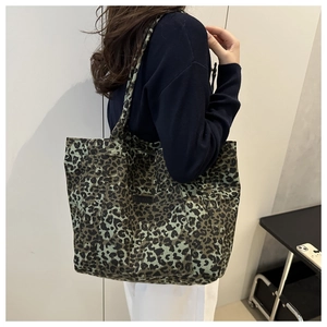 Detail of large leopard print tote bag in green canvas showing strap and front pocket
