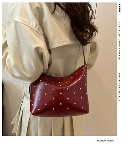 Macro detail of red glossy leather handbag with silver rivets on beige trench coat