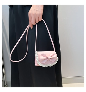 Detailed view of pink mini handbag with a large bow and white lace trim on the flap