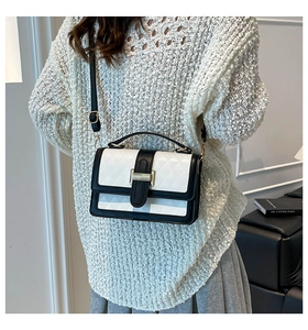 Detail of a black and white geometric embossed crossbody bag on a knit sweater model