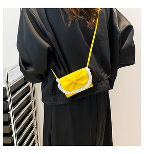 Detailed back view of a bright yellow mini crossbody bag with a cute bow and lace trim