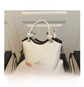 Detail view of white bucket bag with brown handles and adjustable crossbody strap