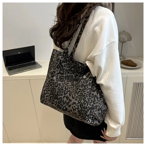 Side view of a large leopard print tote bag worn on shoulder in a modern office setting