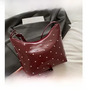 Macro detail of the dark burgundy faux leather bag with silver rivets and metal zipper