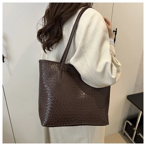 Detail of dark brown tote bag with woven texture and long handles for shoulder wear