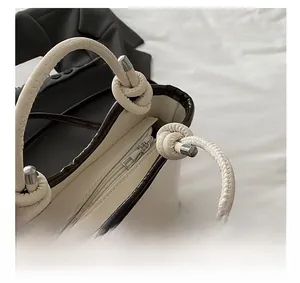 Detail of cream bucket bag showing silver zipper closure and brown crocodile pattern trim