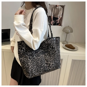 Detail view of leopard print tote bag with front pocket and fashion label on the side